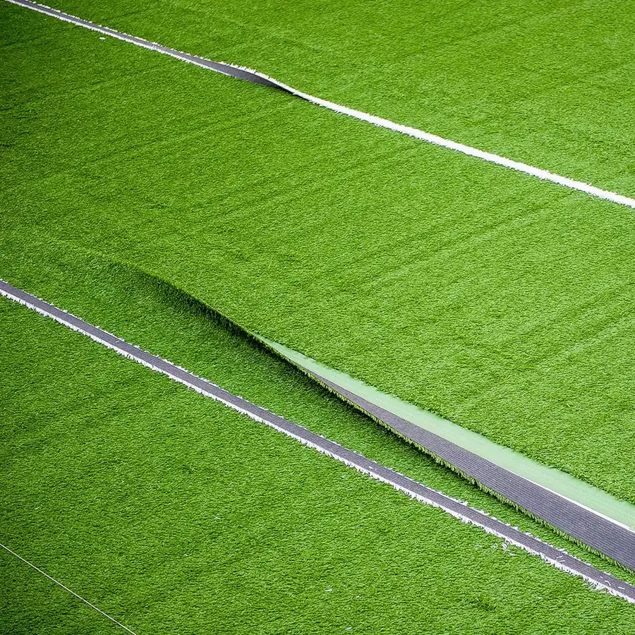 Close-up of artificial grass rolls being seamed and laid during a professional turf installation